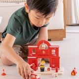 Child playing with the PlanToys fire engine and fire station set