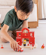 Child playing with the PlanToys fire engine and fire station set