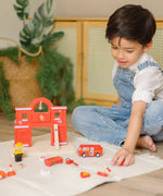 Child playing with loose figures with the PlanToys wooden fire station extension set