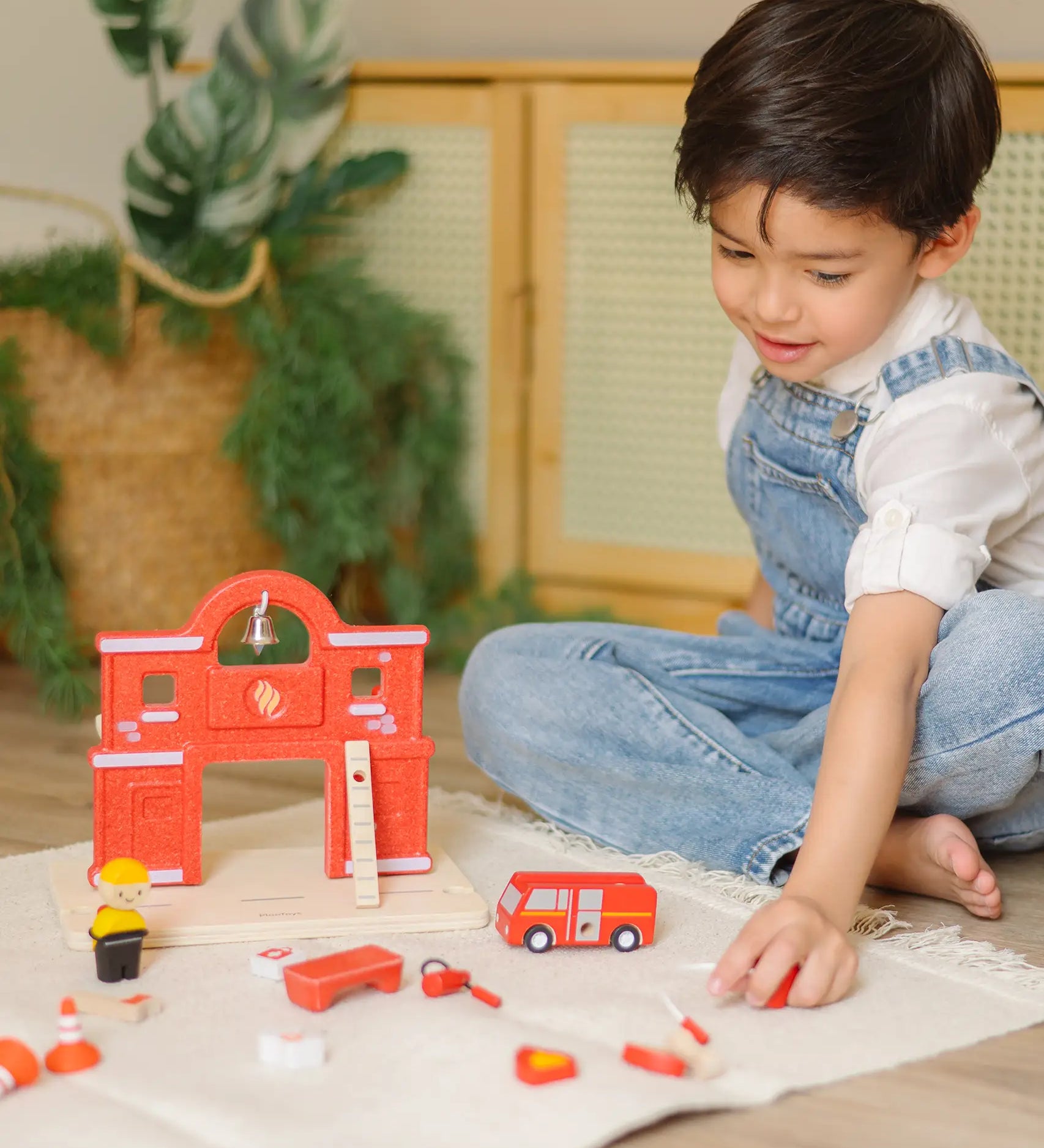 Child playing with loose figures with the PlanToys wooden fire station extension set