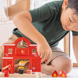 Child playing with the PlanToys fire station extension set showing a fireman figure and other related pieces