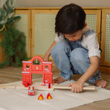 Child connecting a loose PlanToys road piece with the fire station extension set