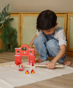 Child connecting a loose PlanToys road piece with the fire station extension set