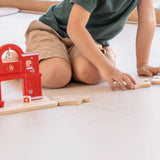 Loose PlanToys road pieces connected with a fire station set