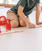 Loose PlanToys road pieces connected with a fire station set