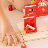 Child connecting a road piece with the PlanToys fire station with a connector