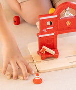 Child connecting a road piece with the PlanToys fire station with a connector