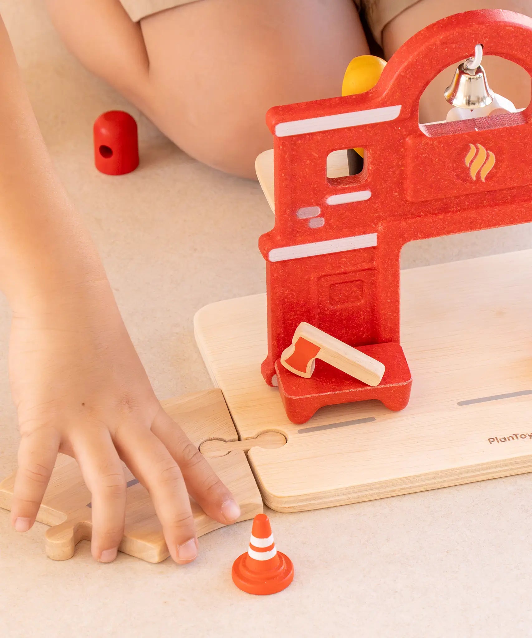 Child connecting a road piece with the PlanToys fire station with a connector