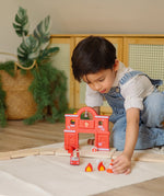 Child placing a small cone in front of a PlanToys fire station and road setup