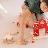 Child connecting PlanToys road pieces with the fire station extension set with wooden connectors 