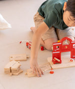 Child connecting PlanToys road pieces with the fire station extension set with wooden connectors 