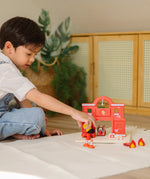 Child playing with the PlanToys fireman figure and fire station set