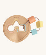 The PlanToys Shape Sorter, is a perfect first shape sorter toy for little ones and babies. Offering a sensory and educational experience, this shape sorter is in a disk shape, was a circle, triangle and square cut out. Attached to the cut out with thing and durable rope is a peach circle block, a yellow triangle block and a blue square block. The image is on a cream background