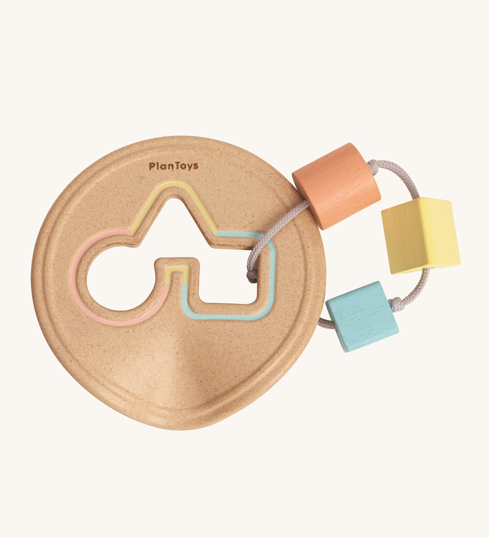 The PlanToys Shape Sorter, is a perfect first shape sorter toy for little ones and babies. Offering a sensory and educational experience, this shape sorter is in a disk shape, was a circle, triangle and square cut out. Attached to the cut out with thing and durable rope is a peach circle block, a yellow triangle block and a blue square block. The image is on a cream background