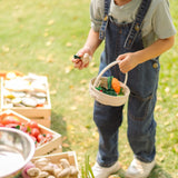 Child holding a PlanToys basket filled with loose wooden veg pieces