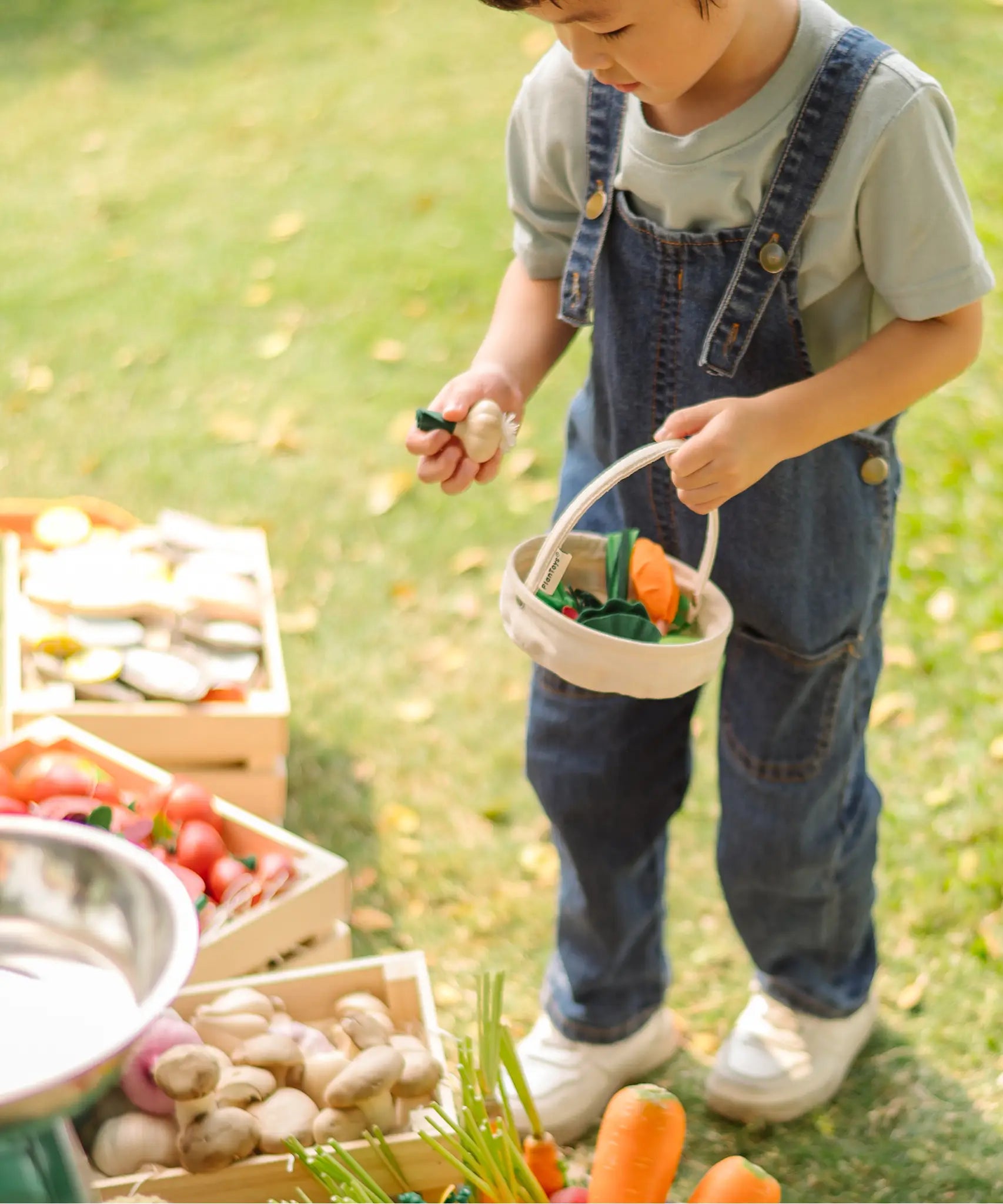 Child holding a PlanToys basket filled with loose wooden veg pieces
