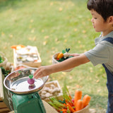 Child carrying a basket filled with wooden veggie pieces and placing some on scales