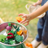 Child placing loose veg pieces from the PlanToys fresh veggie basket set on scales