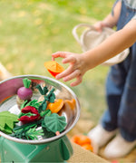 Child placing loose veg pieces from the PlanToys fresh veggie basket set on scales
