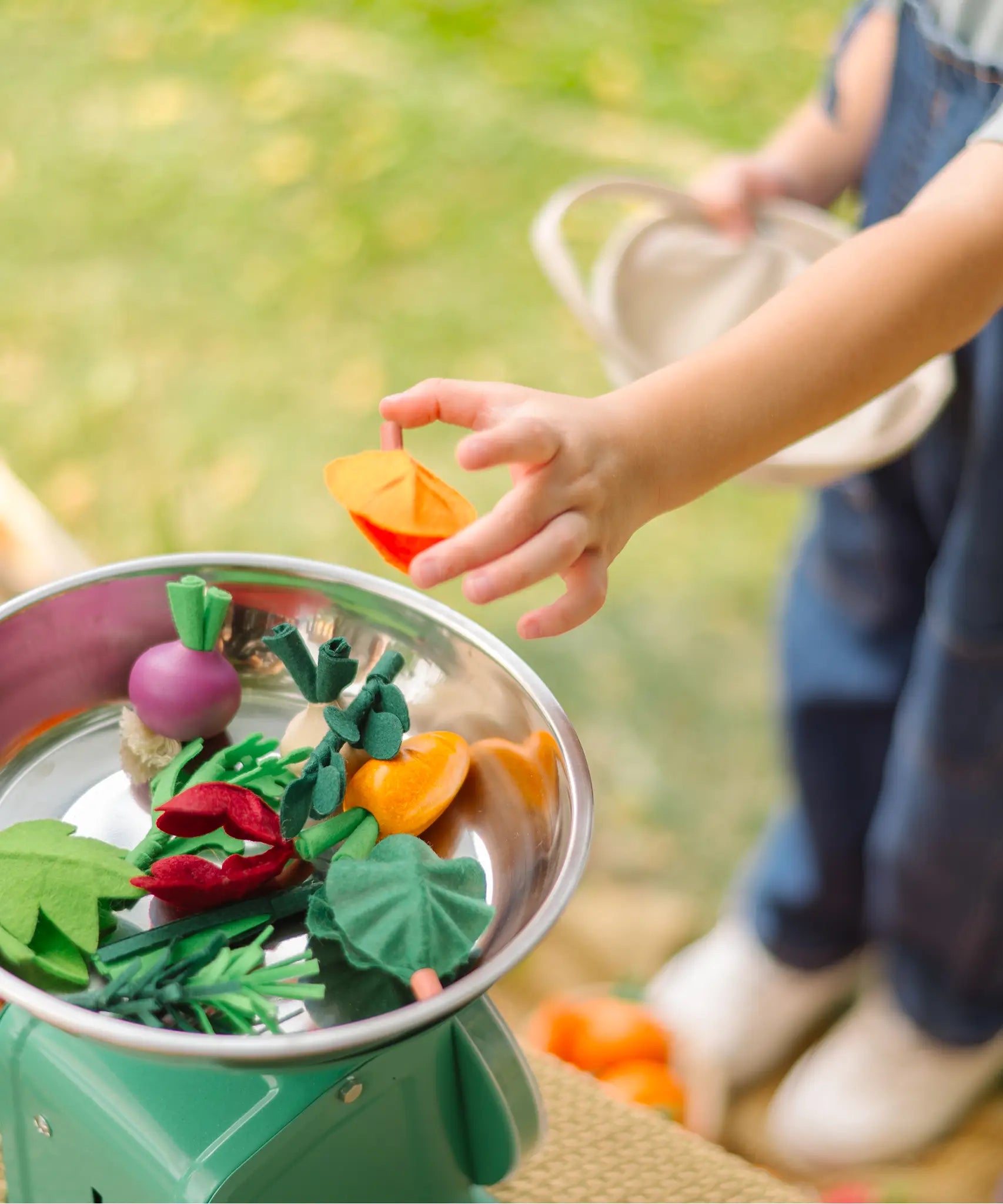 Child placing loose veg pieces from the PlanToys fresh veggie basket set on scales