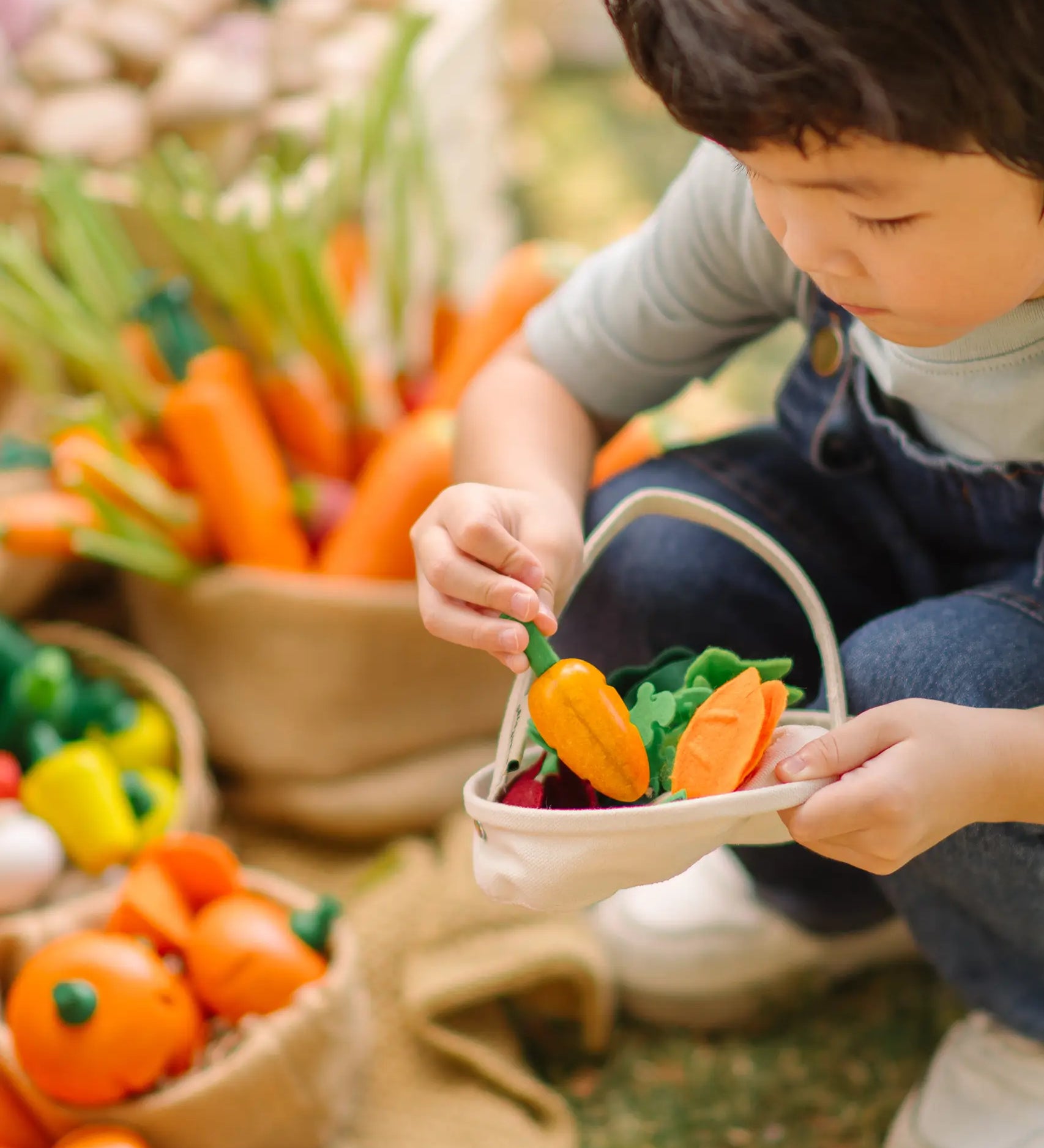 Child filling a PlanToys basket with loose wooden veggie pieces