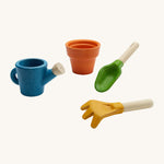 PlanToys Gardening Set is a wooden role play set with a brown plant pot, a green trowel, and yellow rake and a blue watering can. Each piece can be used in messy play and the watering can has a small hole in the spout to allow water to pour through