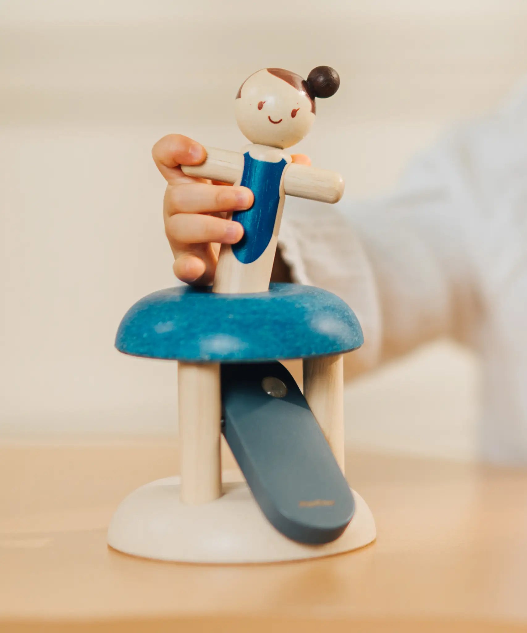Child inserting the PlanToys gymnast peg doll in the base ready to be launched. 