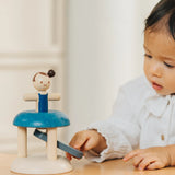 Child pressing down on the working base ready to launch the PlanToys gymnast peg doll