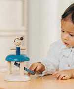 Child pressing down on the working base ready to launch the PlanToys gymnast peg doll