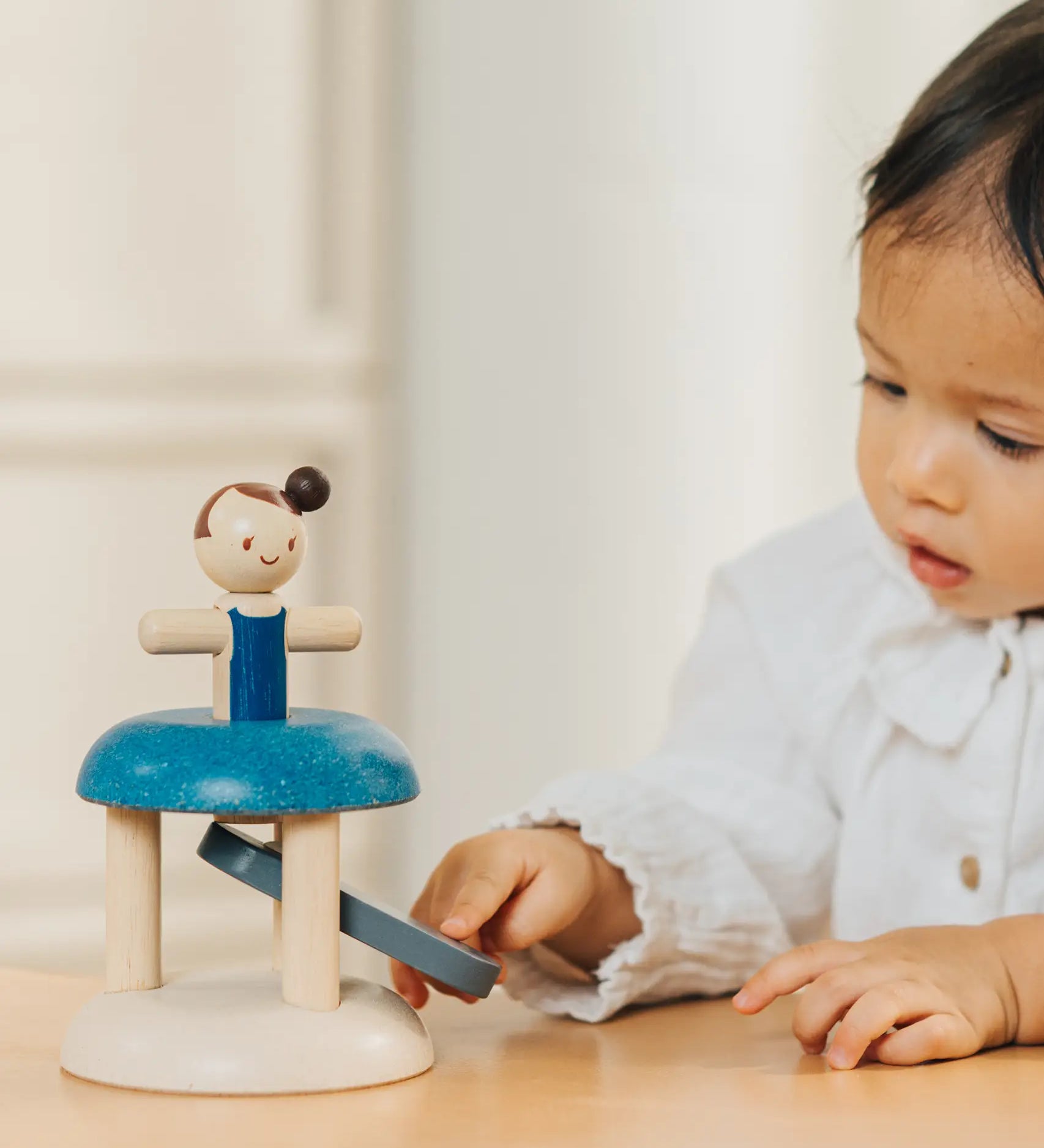 Child pressing down on the working base ready to launch the PlanToys gymnast peg doll