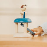 Child's hand pressing down on the base launching the PlanToys gymnast peg doll