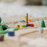 PlanToys wooden jungle explorers road playset showing a camper figure doll sitting next to a backpack and campfire