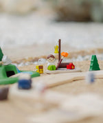 PlanToys wooden jungle explorers road playset showing a camper figure doll sitting next to a backpack and campfire