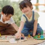 Children playing with toy trucks on the PlanToys wooden jungle explorers road playset on a rug 
