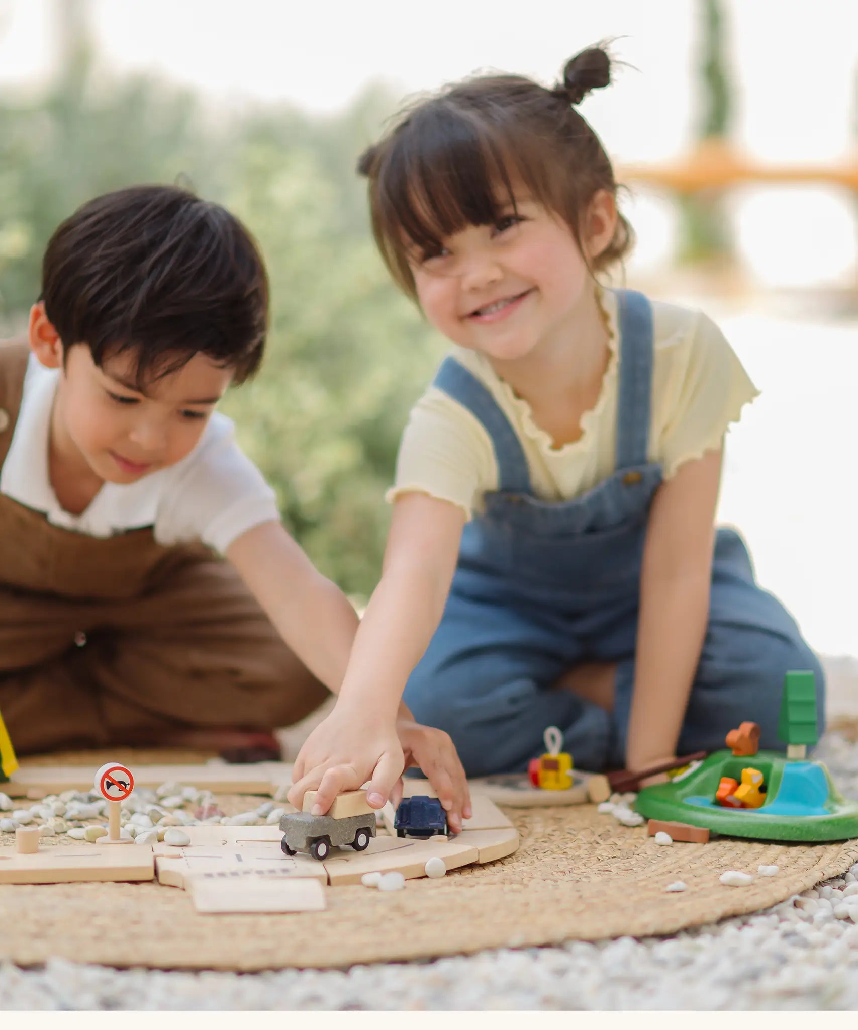 Children playing with toy trucks on the PlanToys wooden jungle explorers road playset on a rug 