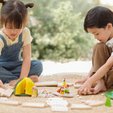 Children assembling road pieces from the PlanToys wooden jungle explorers road playset on a rug in the garden