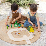 Children playing with the PlanToys wooden jungle explorers road playset on a rug in the garden