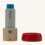 The PlanToys Kaleidoscope, made from PlanWood is in two parts in this image. The part on the left is the main body of the kaleidoscope which is blue and natural wood in colour, and the part on the right is the red lens