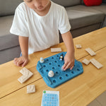 Close up of a child picking up a penguin piece from the Plan Toys eco-friendly wooden finding penguin game on a wooden table