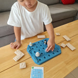 Close up of a child picking up a penguin piece from the Plan Toys eco-friendly wooden finding penguin game on a wooden table