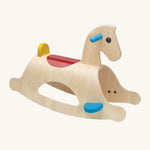 PlanToys Palomino Rocking Horse is a great first rocking horse for children. The rocking horse is made from wood, and shows the natural wood grain. Blue foot plates and handles, a red saddle section on the back of the rocking horse, and a small yellow back support. The mage is on a cream background