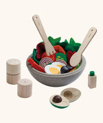 PlanToys wooden little chef's salad set. showing playfood inside a bowl and cutlery hovering above 