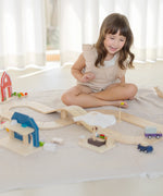 PlanToys little wooden neighbourhood roadway set up on a white blanket