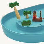 The palm trees from the PlanToys Water Play Set are removable and the image shows the little holes where the trees can slot in. The image is on a cream background