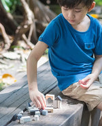 Child playing with small wooden building blocks mini travel set by plantoys outdoors. 