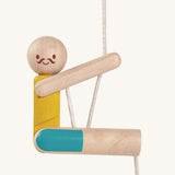 A closer look at the PlanToys Rope Climbing Acrobat. The figure has a happy, smiling face and mustache , a yellow painted top and blue painted shorts. The PlanToys paint is natural and safe. The image is on a cream background.