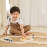Child playing with the PlanToys my first wooden rail road set holding a yellow suv vehicle 