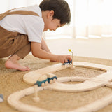 Child playing with the PlanToys my first wooden rail road set holding a blue suv vehicle 