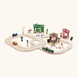 A small town setup made from different PlanToys wooden playsets including a rail road, bakery, vets and a ice cream shop