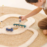 Child playing with the PlanToys my first wooden rail road set holding wooden man figure above a train